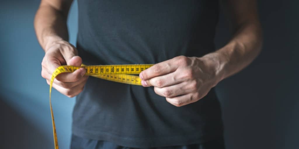 Slim man measuring his waist