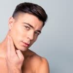confident handsome guy touching with shaved flawless clean soft skin after morning shaving