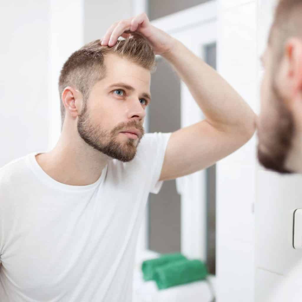 Man checking hairline, in a bathroom