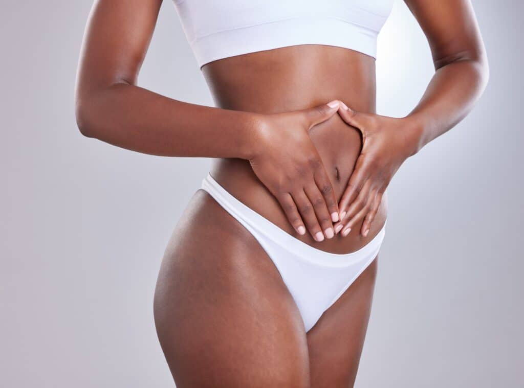 Woman framing her stomach with hands, symbolizing liposuction, tummy tuck, and body contouring for wellness and aesthetics