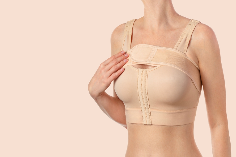 Woman wears compression bra after having breast augmentation surgery