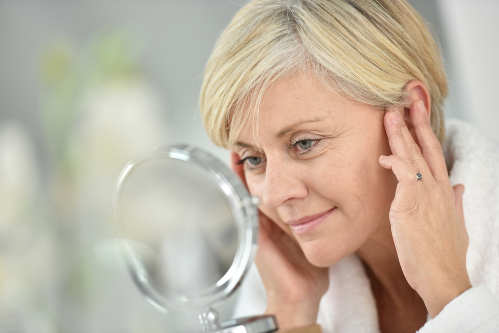 Woman in her late 50s looks at her eyes wishing to do something about signs of aging.